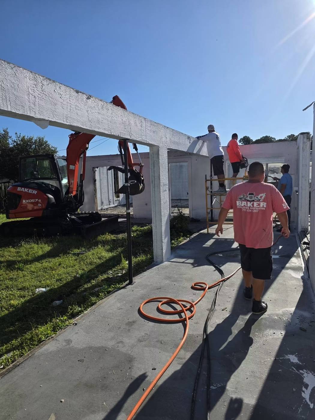 Crew and excavator performing structural demolition on a building