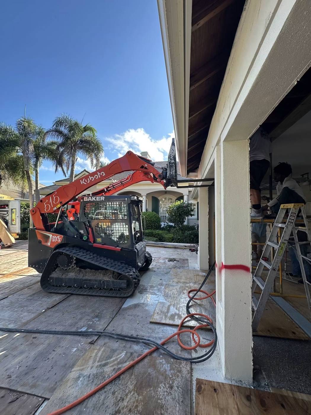 Baker Demolition & Construction compact track loader reaching a roofline for removal work